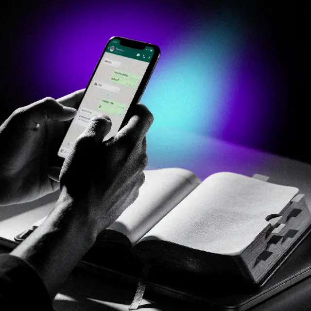 Manos sosteniendo un celular con una conversación de WhatsApp junto a una agenda abierta